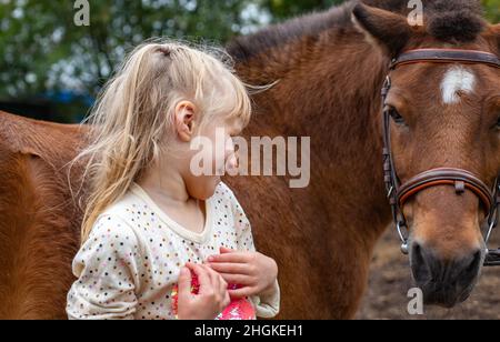 piccola ragazza ridere con cavallo pony in club equestre Foto Stock