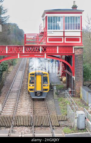 Red victorian Signal box e ponte presso la stazione ferroviaria di Wylam Northumberland con treno pendolare che parte dalla stazione dall'alto Foto Stock