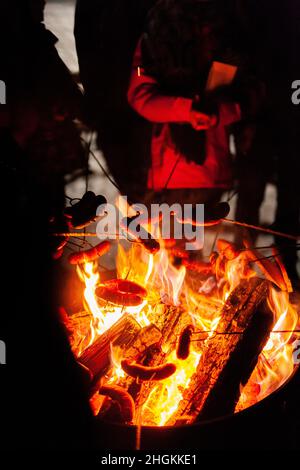 arrostire le salsicce al fuoco in inverno Foto Stock