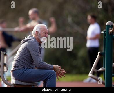 Uomo anziano che riposa dopo un duro workout a e palestra pubblica all'aperto Foto Stock