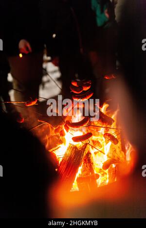 arrostire le salsicce al fuoco in inverno Foto Stock