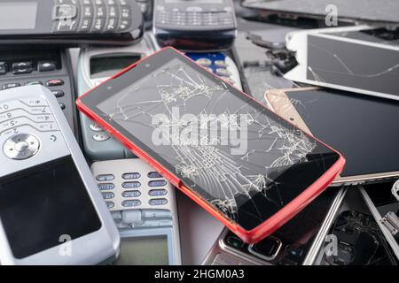 Un mucchio di vecchi smartphone e telefoni cellulari usati con tastiere, molti tipi e generazioni di dispositivi per smartphone, vista dall'alto, messa a fuoco selettiva, c Foto Stock