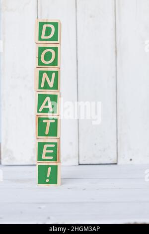 cubo di legno, con la parola donate, su sfondo bianco Foto Stock