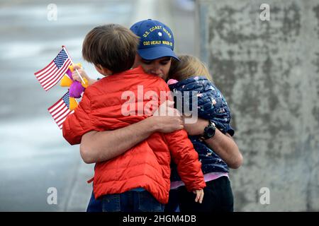 Seattle, Stati Uniti. 20 novembre 2021. Il comandante dell'USCG Philip Baxa, funzionario operativo a bordo della Guardia Costiera degli Stati Uniti Cutter Healy, abbraccia la sua famiglia al molo di base Seattle dopo un dispiegamento di 22.000 miglia, 133 giorni che circumnavigava il Nord America, 20 novembre 2021 a Seattle, Washington. Credit: PO3 Michael Clark/US Coast Guard Photo/Alamy Live News Foto Stock