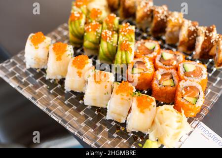 Cucina giapponese a soffitto con sushi. Maki Sands Rolls con tonno, salmone, gamberi, granchio e avocado. Vista dall'alto di sushi assortiti, menu a volontà. Arcobaleno Foto Stock