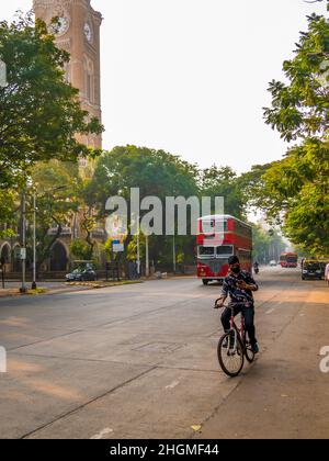 MUMBAI, INDIA - 26 novembre 2021 : uomo non identificato che guida una bicicletta indossando la maschera covid-19 e guardando il mobile. Guida non sicura. Foto Stock