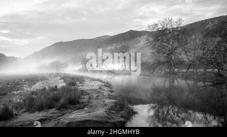 Bianco e nero splendido paesaggio autunnale immagine dell'alba guardando verso Borrowdale Valley da Derwentwater nel Lake District con nebbia che si estende attraverso la t Foto Stock