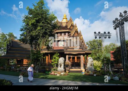 A Wat Sanghathan, un tempio di meditazione a Nonthaburi, in Thailandia, una suora cammina davanti a uno dei padiglioni ornati del tempio. Foto Stock