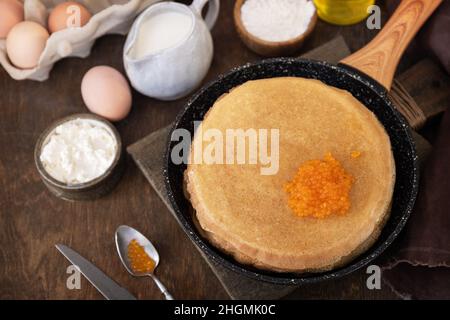 Frittelle di cucina tradizionale russa. Pancake sottili serviti con caviale rosso su un tavolo di legno. Foto Stock