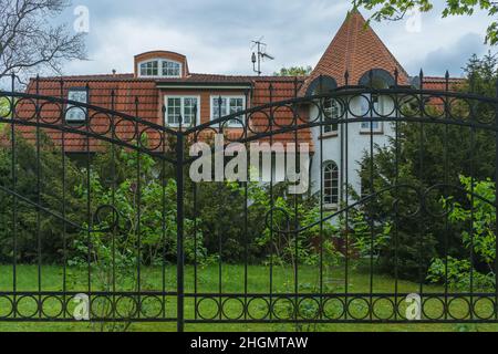 Kaliningrad, Russia - 16 maggio 2021: Facciata della casa e giardino su recinzione di ferro Foto Stock