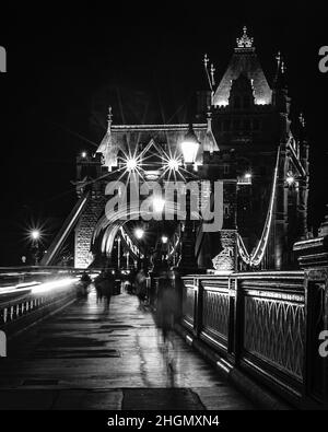 Immagine monocromatica del Tower Bridge di Londra, con percorsi a semaforo che passano sopra il ponte, in prima serata. Foto Stock