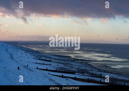 La vista ad ovest dalla spiaggia di Herne Bay guardando verso l'Isola di Sheppey e il Molo Hampton durante il bordo posteriore di una doccia pesante della neve nel febbraio 2021. Foto Stock