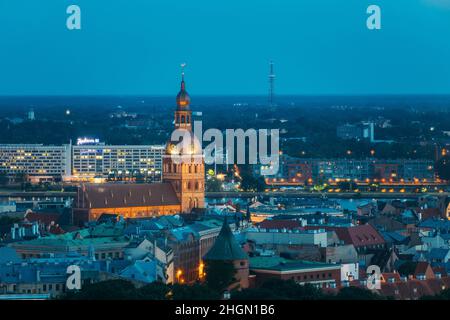 Riga, Lettonia. Vista aerea del paesaggio urbano in Estate sera luci notturne illuminazione. Vista dall'alto della Cattedrale del Duomo di riga. Chiesa famosa e punto di riferimento Foto Stock