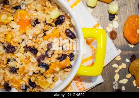 Cibo dietetico, farina d'avena con frutta secca su un tavolo di legno Foto Stock