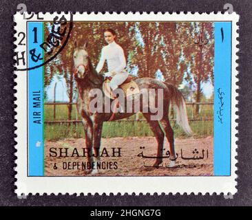 Cancellò francobollo stampato da Sharjah e dipendenze, che mostra equitazione, circa 1972. Foto Stock