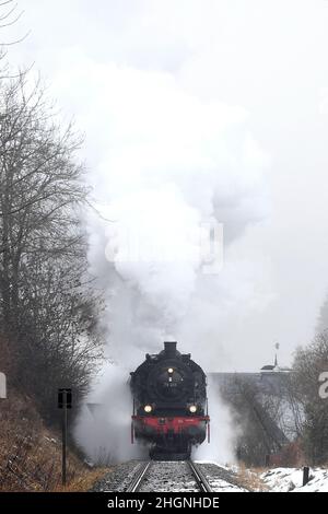 Winterberg, Germania. 22nd Jan 2022. Un treno storico passa attraverso il villaggio innevato. La storica locomotiva a vapore è un T18 prussiano del 1920s. Con il titolo "Toboggan Steam to the Sauerland", la Bielefeld Railway Friends Association guida una storica locomotiva a vapore da Bielefeld a Winterberg. A bordo ci sono diverse centinaia di fan della ferrovia, che slittano sulle piste con le loro slitte a destinazione. Il treno si ferma anche a Paderborn, Lippstadt, Soest, Unna e Arnsberg, tra gli altri luoghi. Credit: David Inderlied/dpa/Alamy Live News Foto Stock