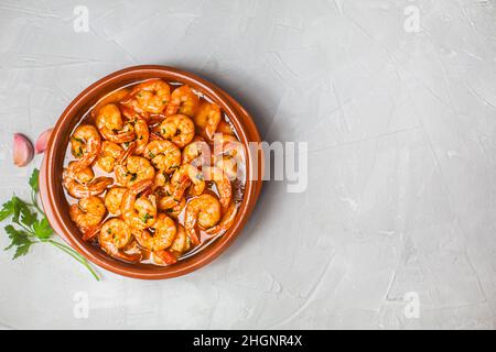 Gamberi spagnoli tradizionali con aglio su sfondo grigio moderno con spazio copia. Generalmente viene preparato con olio d'oliva Foto Stock