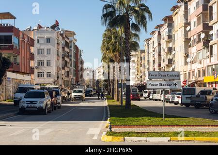 Manavgat, Turchia -20 gennaio 2022: Strada della città con diverse case basse, traffico auto attivo, negozi Foto Stock