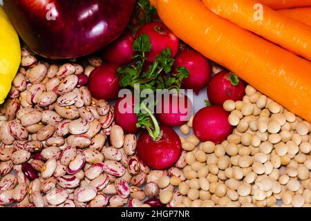 cibo vegano: fagioli di pinto, ravanelli, carote, mela rossa e soia Foto Stock