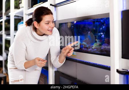 Ragazza in negozio acquario punti a pesci colorati Foto Stock