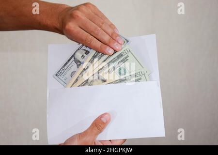 Soldi in una busta bianca nelle mani di un uomo. Dollari, una follia di dollari. Foto Stock