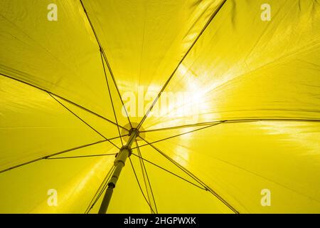 Particolare di un ombrello giallo con sole luminoso Foto Stock
