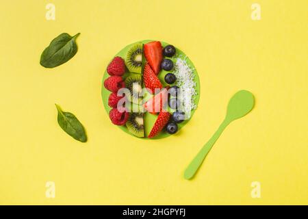 ciotola per frullati con frutti e bacche fresche in un piatto di carta artigianale giallo Foto Stock