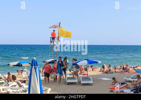 Blanes, Catalogna, Spagna. - 25 luglio 2017, spiaggia comunale. Il bagnino sulla torre si affaccia sul mare. La gente lascia la spiaggia Foto Stock