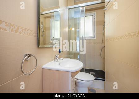 Bagno completo con lavandino in porcellana bianca e doccia sul retro, specchio senza cornice e portasciugamani Foto Stock