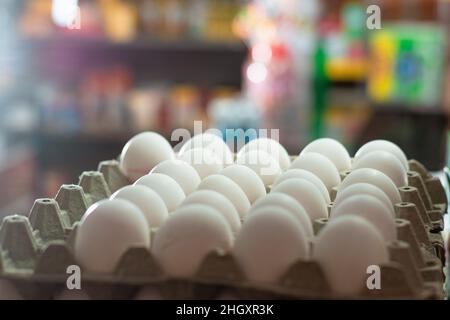 vista di diverse uova bianche di gallina, poste in una vetrina di vetro. vendita di uova in un negozio di alimentari. uova ricche di proteine albumina pronte per essere vendute e con Foto Stock