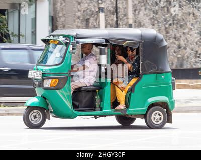 Risciò auto verde, chiamato anche tuk-tuk, con due passeggeri femminili, a Colombo, Sri Lanka Foto Stock