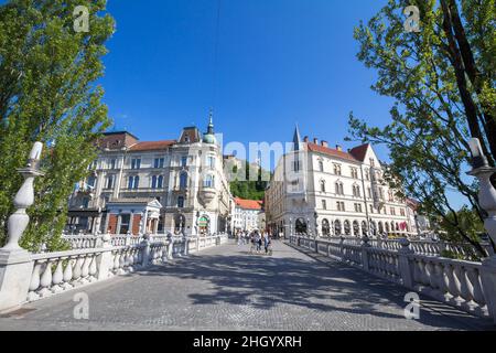 Foto di persone che camminano sul ponte di Tromostovje (ponte triplo) tra piazza Presernov e la parte più antica di Lubiana durante una soleggiata estate afterno Foto Stock