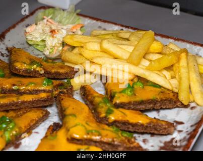 Focalizzazione selettiva delle patatine fritte e delle piccole fette di pane tostato al peperoncino su un piatto di antipasti. Foto Stock