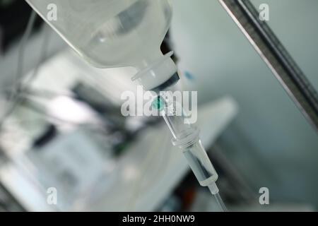Sistema di gocciolamento endovenoso appeso al cavalletto di ferro nella stanza dell'ospedale. Foto Stock
