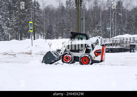 trattore rosso di colore piccolo che cancella la vista laterale della neve Foto Stock