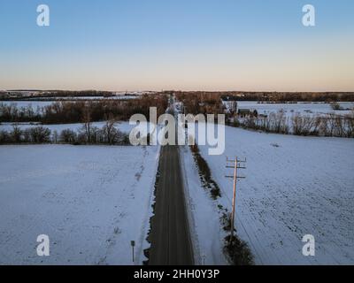 Strada punto di fuga con paesaggio invernale in zona rurale. Foto Stock