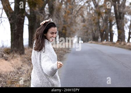 Giovane donna elegante sulla strada asfaltata nella stagione fredda. Foto Stock
