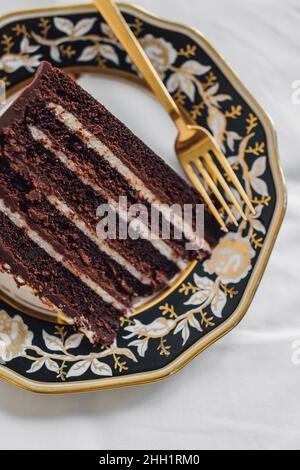 Torta al cioccolato Diavolo's Food su un piatto d'oro bianco nero con forchetta d'oro Foto Stock