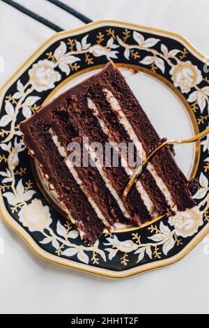 Torta al cioccolato Diavolo's Food su un piatto d'oro bianco nero con forchetta d'oro Foto Stock