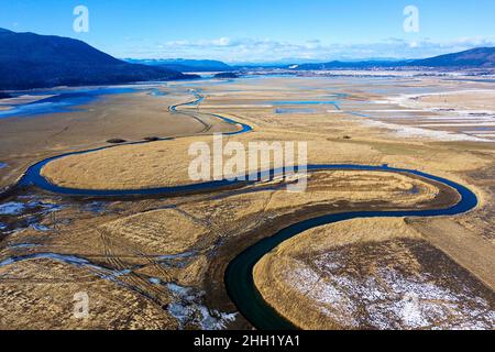 Vista dall'alto dell'affluente che sfocia nel lago di Cerknica, splendida vista sul lago e sulle montagne frozen intermittenti, presa dal drone, Slovenia Foto Stock