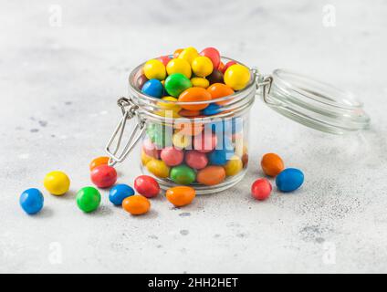 Varie caramelle dolci al cioccolato al latte con un centro di riso in un guscio di zucchero in vaso di vetro su un tavolo leggero. Foto Stock