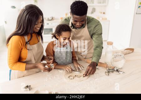 Famiglia Africana americana che fa i biscotti usando le forme di cottura in cucina Foto Stock