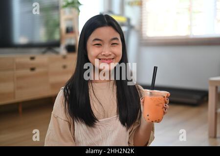 Ragazza asiatica carina che tiene una tazza di tè del latte della bolla della perla. Foto Stock