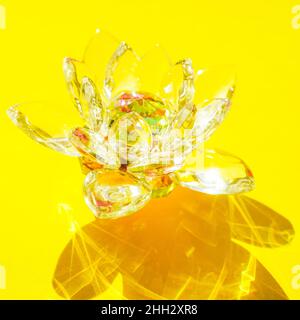 Bellissimo fiore di cristallo di loto su un tavolo giallo soleggiato. Foto Stock