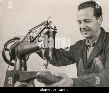 Lettonia - CIRCA 1930s: Vintage archivio foto di cobbler riparazioni scarpe di lusso in pelle fatte a mano. Giovane uomo che lavora in un laboratorio di cordwainer Foto Stock