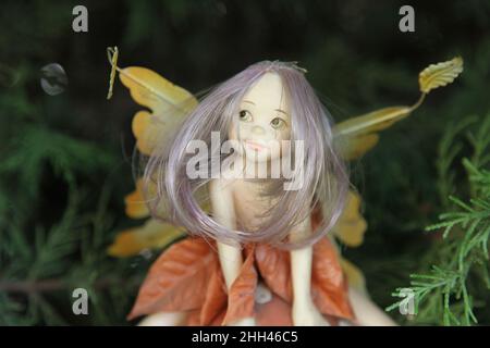 Una fata dai capelli lunghi con ali figurine seduta in giardino. Primo piano Foto Stock