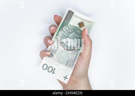 Cento zloty - banconota polacca. Valuta polacca tenuta in mano su sfondo bianco Foto Stock