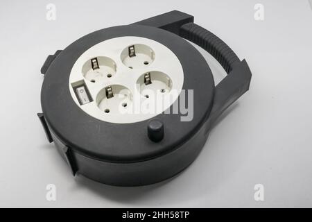 Prolunga in rotolo per cavi industriali flessibile nera con sfondo bianco. Questo rullo per cavi viene solitamente utilizzato per i tecnici o i meccanici che hanno bisogno di elettricità Foto Stock