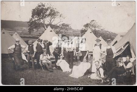 Gruppo di uomini campeggio a Scarborough, 1911. Le grandi tende campanari sono sullo sfondo e gli uomini ridono e mucchiano per la macchina fotografica - una viene pulita con una spugna e un'altra viene lavata con una lattina d'acqua Foto Stock