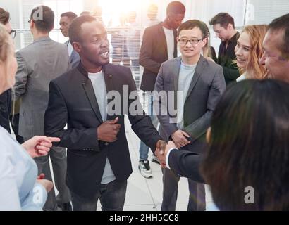 Due busines interculturale handshaking partner dopo la firma del contratto di partenariato con alcuni colleghi nelle vicinanze Foto Stock